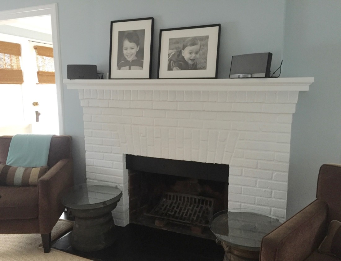 White brick fire place with picture frames on the mantel